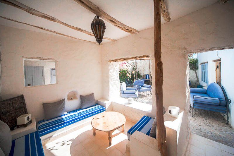 Le salon aux murs blanchis, banquettes bleues et table basse