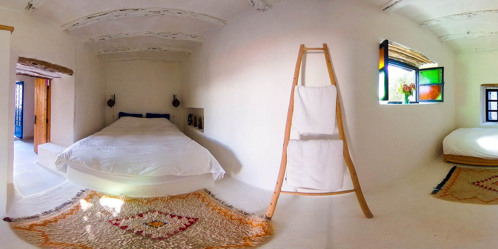 La chambre principale aux murs blancs, lit double, lit simple et tapis berbère