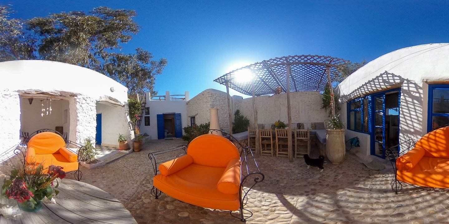 Le patio de la White Kasbah, murs blanchis à la chaux, portes bleues et fauteuil orange